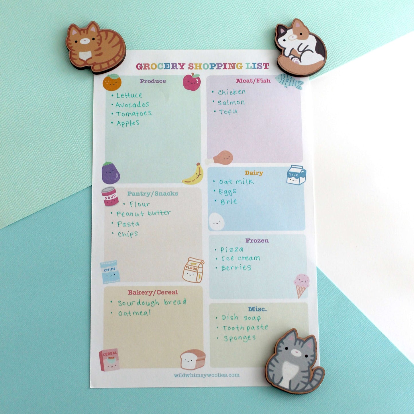 Grocery shopping list with three cat-themed magnets on a blue and white background