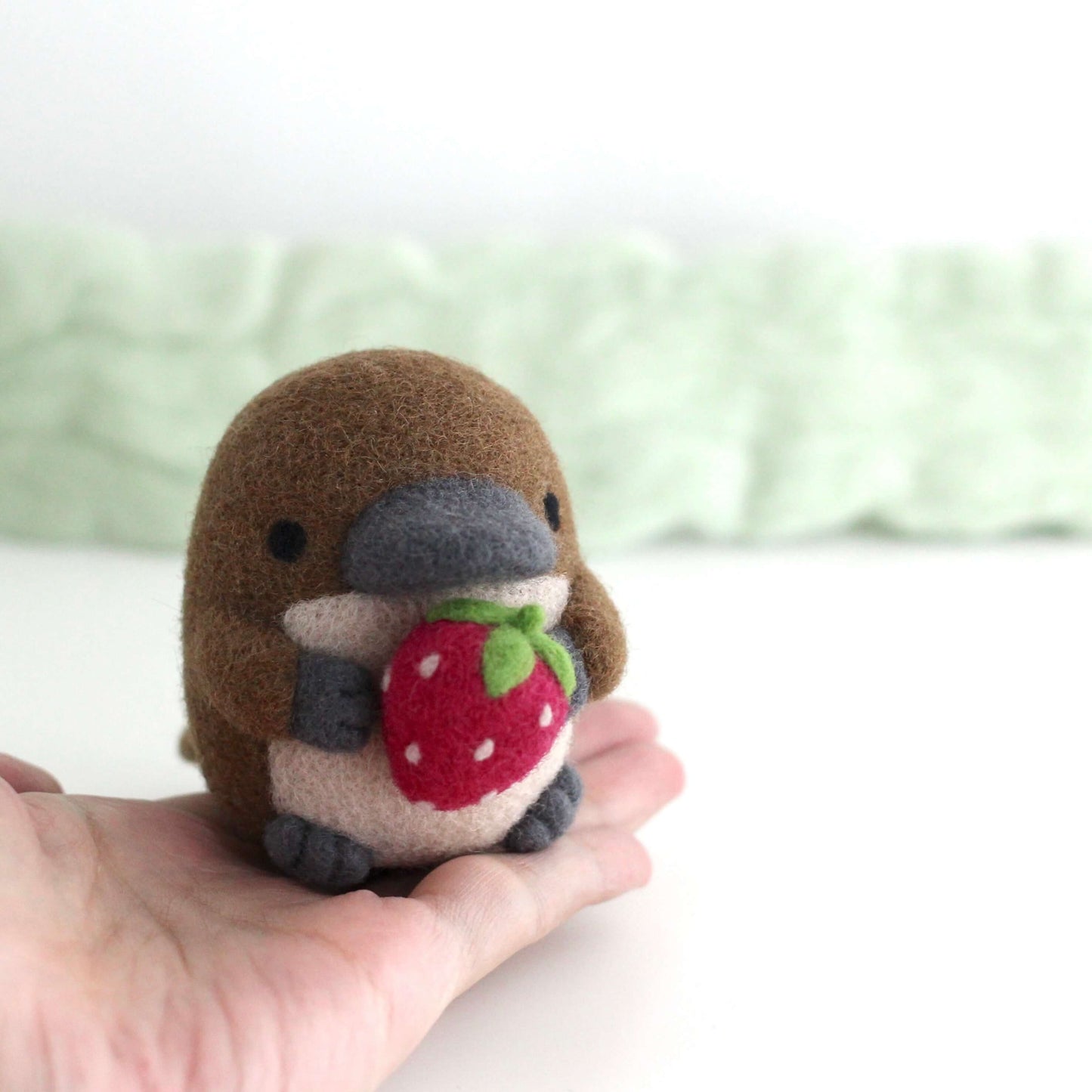 Needle Felted Platypus Holding Dark Red Strawberry