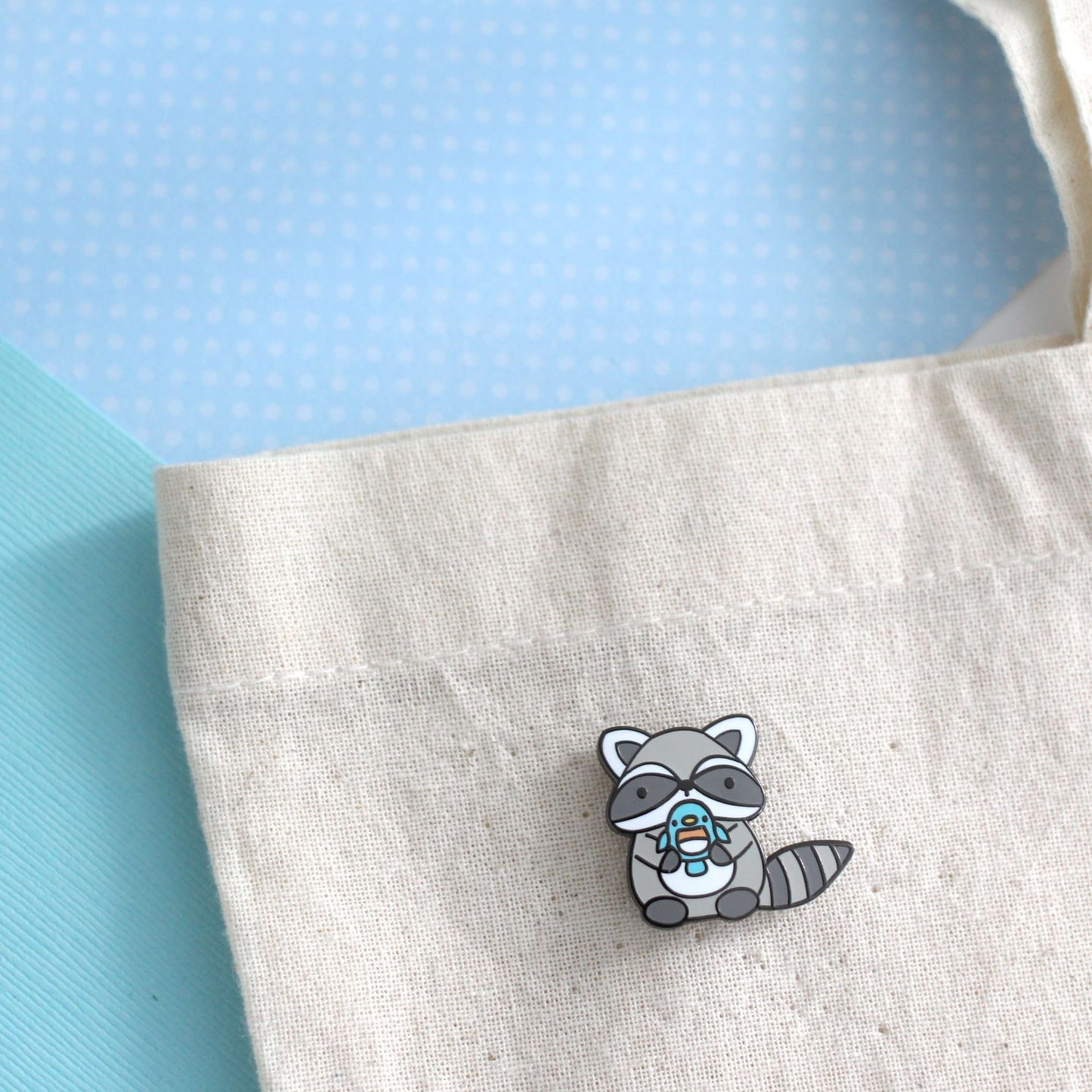 Raccoon holding Blue Bird Enamel Pin