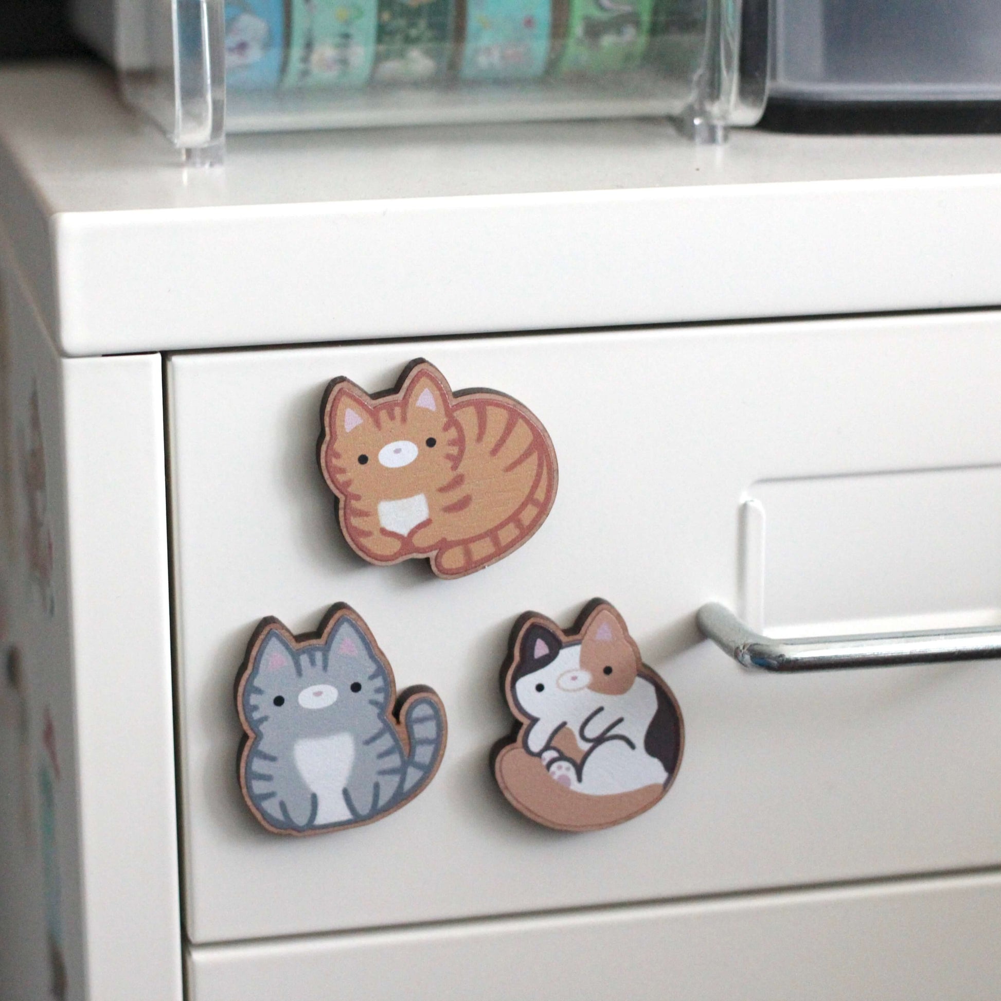 Three cat-shaped magnets on a refrigerator door
