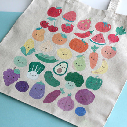 Close up of a tote bag with print of colorful fruits and vegetables with smiling faces. 