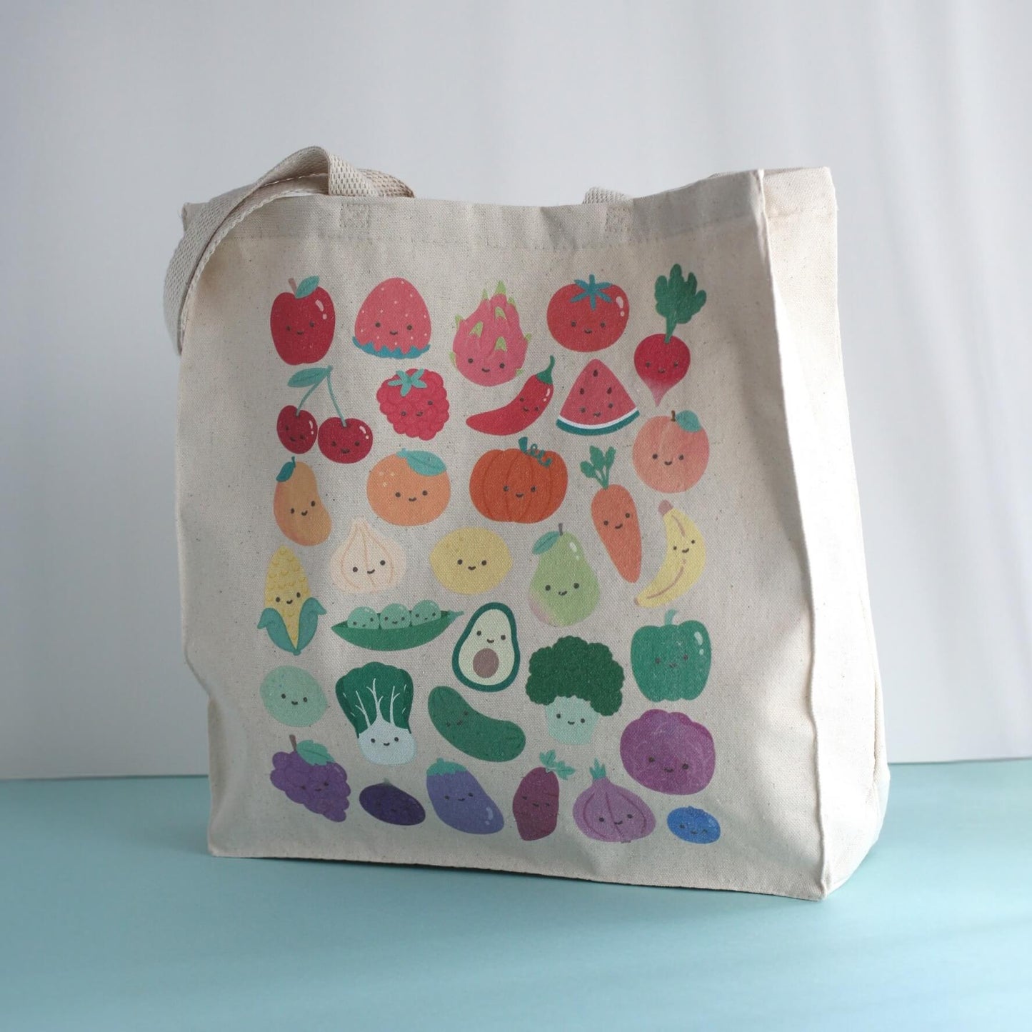 Standing tote bag with print of colorful fruits and vegetables with smiling faces.